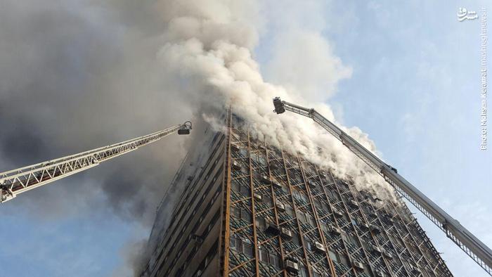 عکس/ تلاش برای خاموش کردن آتش پلاسکو از روی نردبان